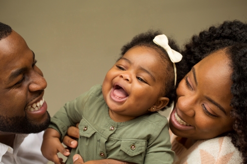 A Black man and woman holding a smiling baby.
