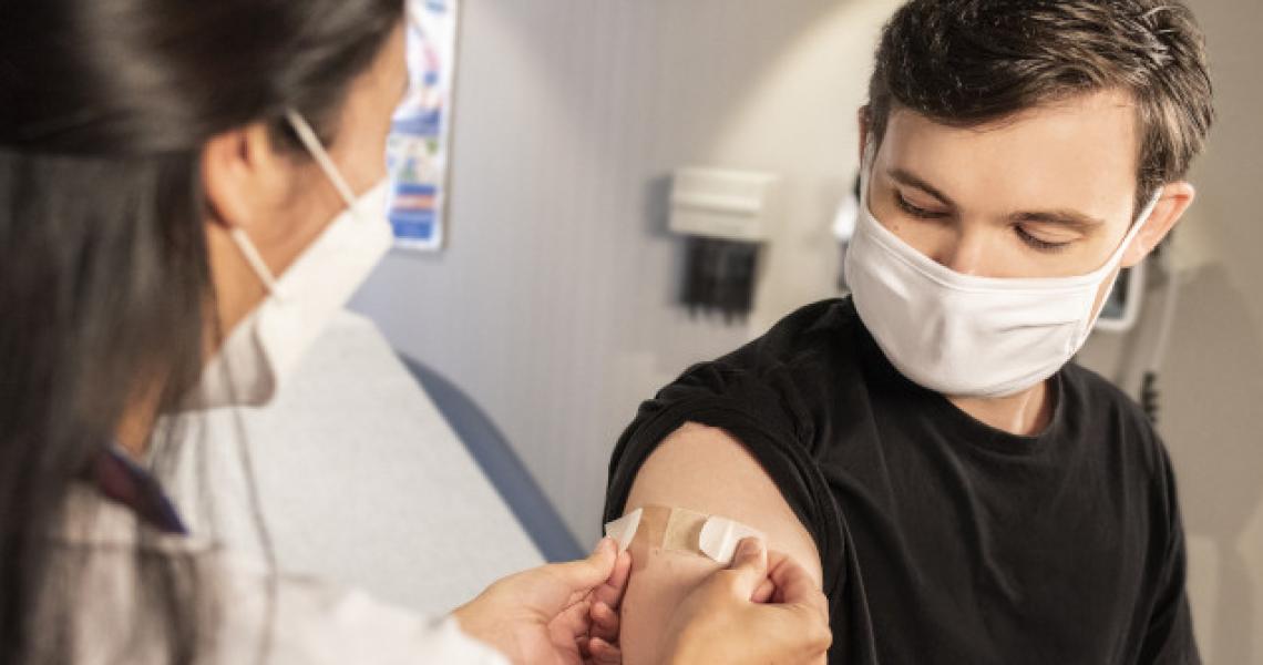 A white man receiving a vaccine from a nurse.