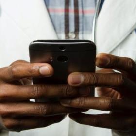 A Black doctor holding a phone.
