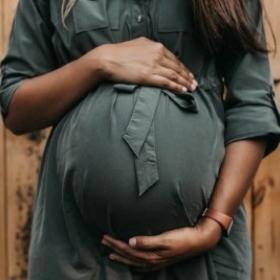 A Black pregnant woman holding her stomach.